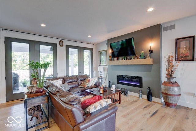 living room featuring recessed lighting, wood finished floors, visible vents, french doors, and a glass covered fireplace