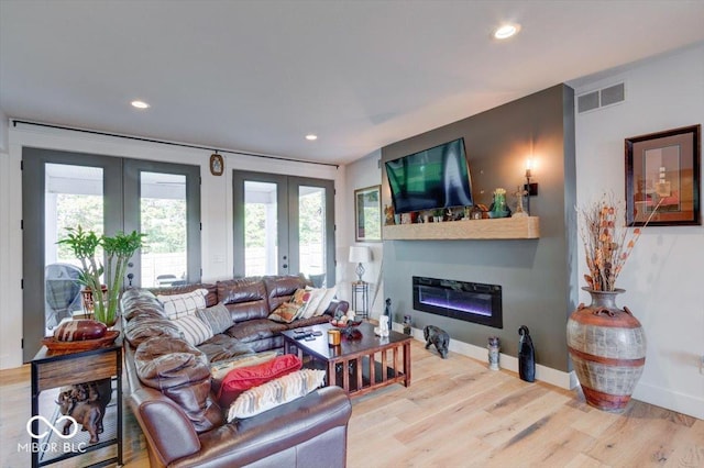 living area with recessed lighting, wood finished floors, visible vents, french doors, and a glass covered fireplace