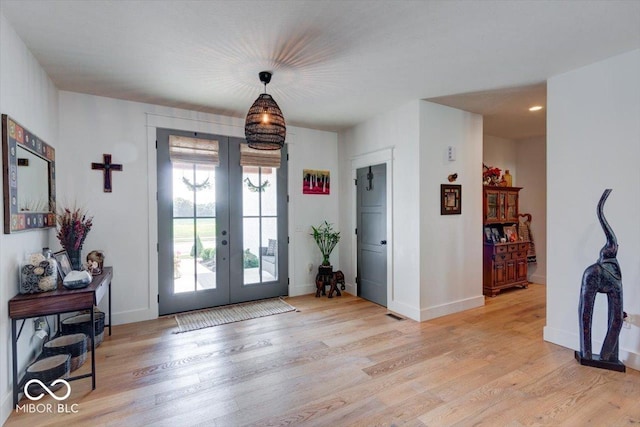 entryway with light wood-type flooring, baseboards, and french doors