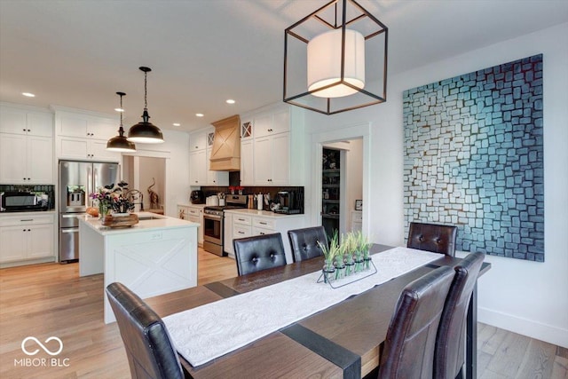 dining area featuring light wood finished floors, baseboards, and recessed lighting