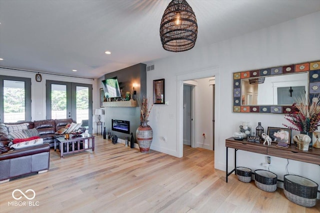 living room with french doors, recessed lighting, a glass covered fireplace, wood finished floors, and baseboards