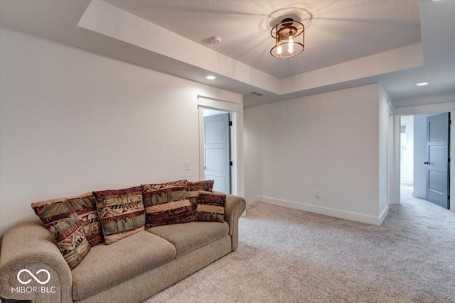 carpeted living room with a tray ceiling, recessed lighting, visible vents, and baseboards