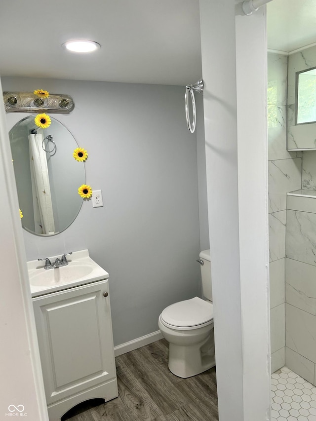 full bath with baseboards, a shower, toilet, wood finished floors, and vanity