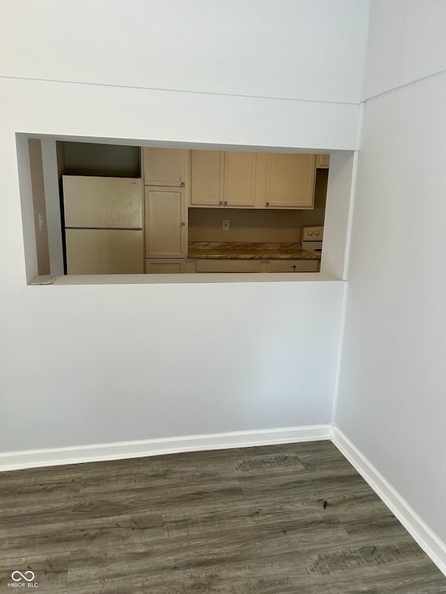 interior space with dark wood finished floors, freestanding refrigerator, and baseboards