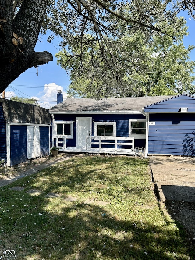 view of front of property with a shed, a chimney, a front lawn, and an outdoor structure