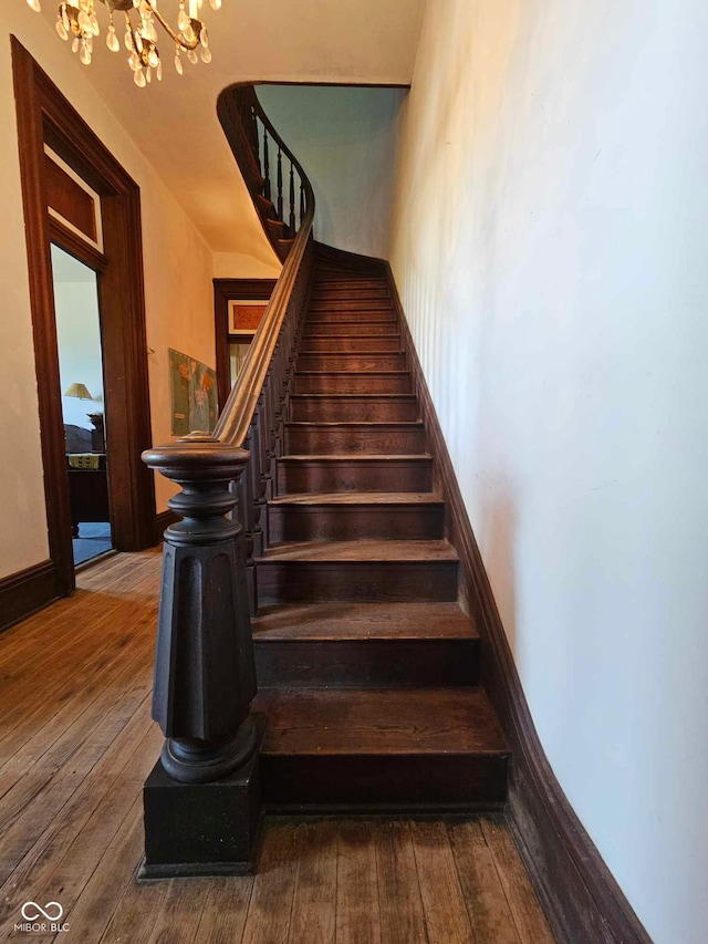 staircase with hardwood / wood-style flooring and an inviting chandelier