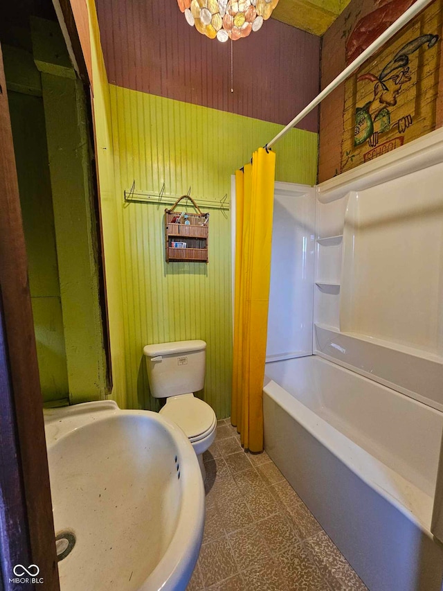 full bathroom featuring sink, wooden walls, toilet, and shower / bathtub combination with curtain