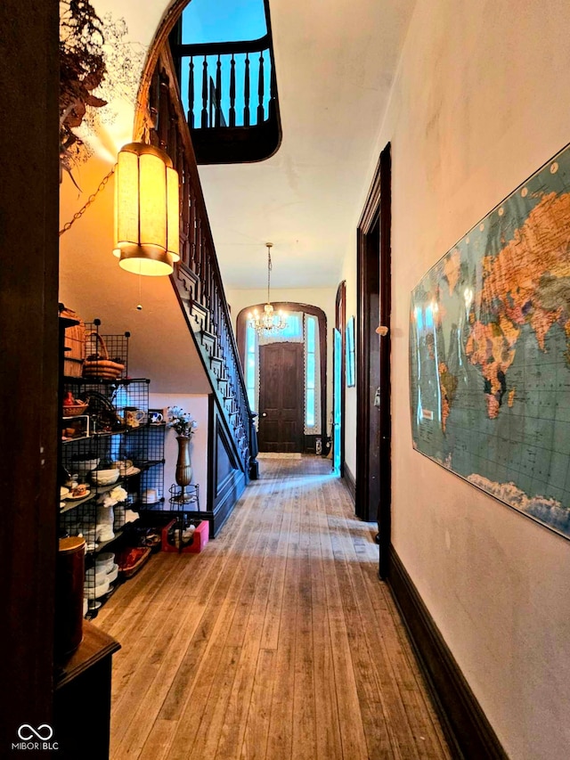 hallway with hardwood / wood-style flooring and a chandelier