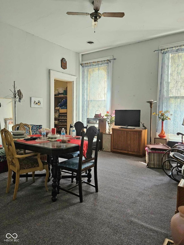 carpeted dining space with plenty of natural light and ceiling fan