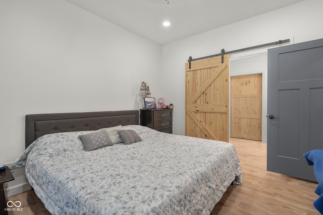 bedroom featuring a barn door and hardwood / wood-style flooring