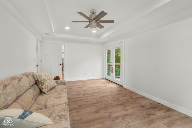 unfurnished living room with light wood-type flooring, a tray ceiling, and ceiling fan