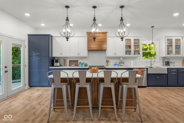 kitchen with light hardwood / wood-style floors, pendant lighting, a kitchen bar, blue cabinets, and stainless steel dishwasher