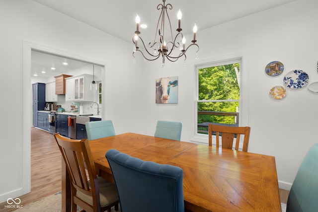 dining room with sink, an inviting chandelier, and light hardwood / wood-style flooring