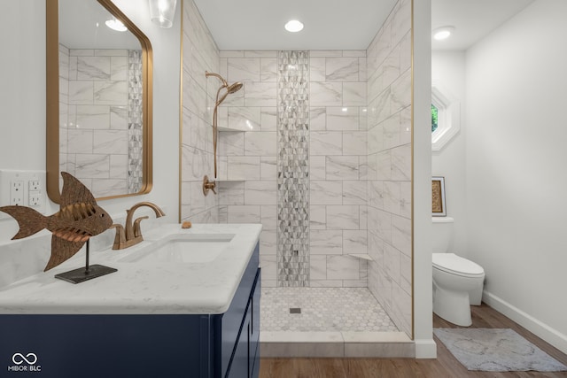 bathroom featuring vanity, toilet, hardwood / wood-style floors, and tiled shower