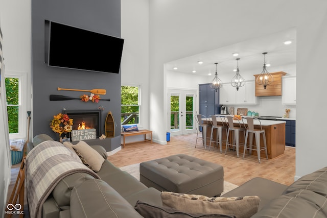 living room featuring a towering ceiling, a wealth of natural light, and light hardwood / wood-style floors