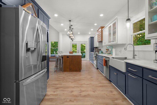 kitchen featuring light hardwood / wood-style flooring, stainless steel appliances, a kitchen island, sink, and white cabinets