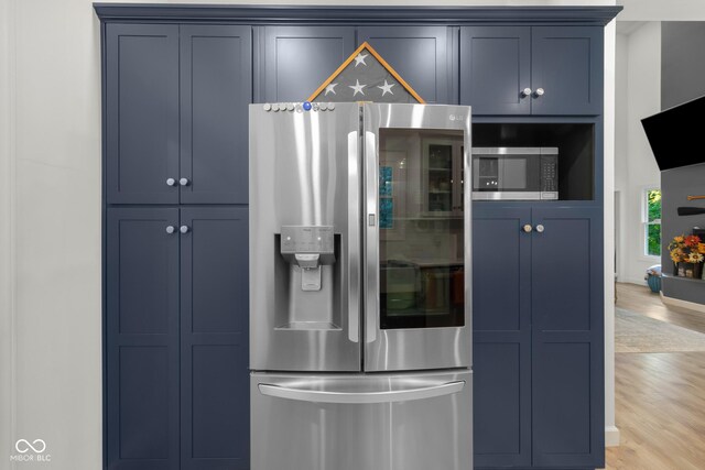 kitchen with appliances with stainless steel finishes, light hardwood / wood-style floors, and blue cabinetry