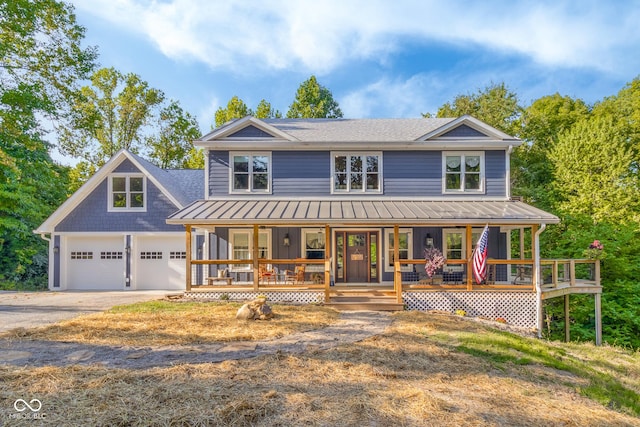 view of front facade featuring a porch, metal roof, a garage, driveway, and a standing seam roof