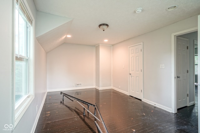 bonus room featuring a textured ceiling, vaulted ceiling, and dark hardwood / wood-style floors