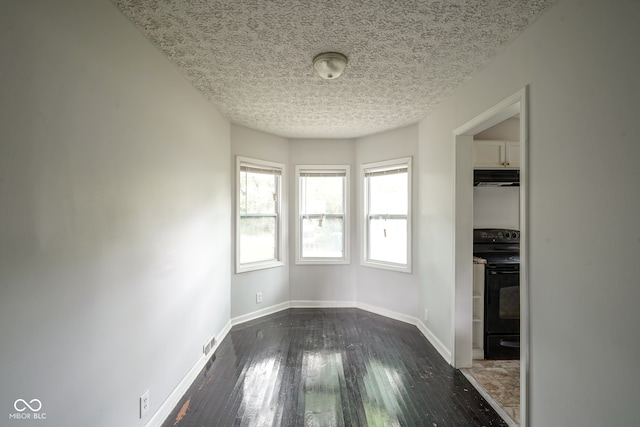 spare room featuring dark hardwood / wood-style flooring and a textured ceiling