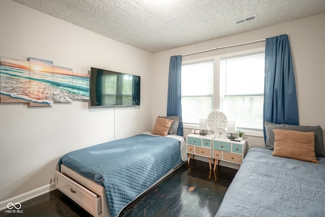 bedroom with dark hardwood / wood-style floors and a textured ceiling