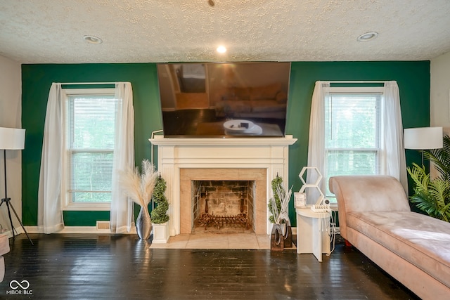 living room with a tiled fireplace, dark hardwood / wood-style flooring, and a textured ceiling