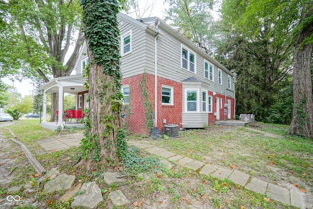 exterior space with central AC unit and a lawn