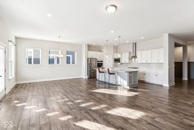 kitchen with a breakfast bar, decorative light fixtures, white cabinetry, and a kitchen island with sink