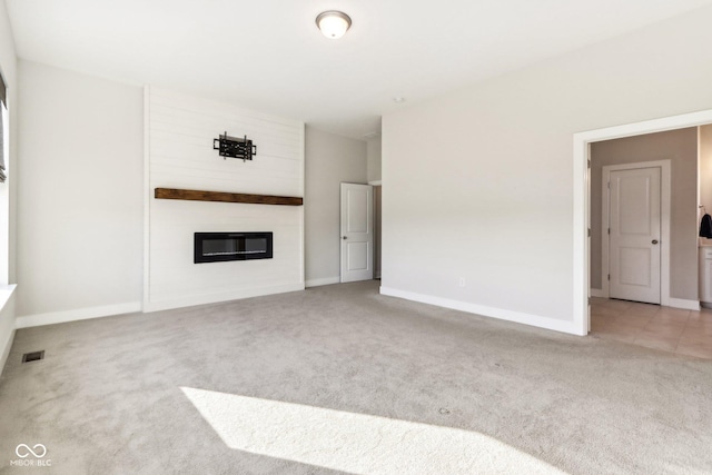 unfurnished living room featuring a large fireplace and carpet floors