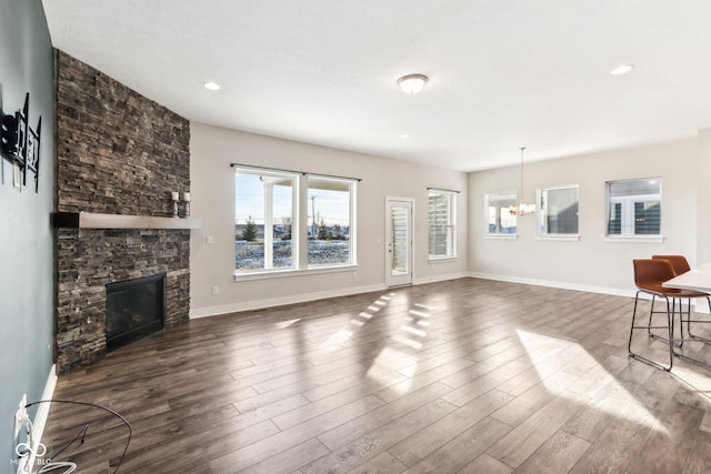 living room with an inviting chandelier, a fireplace, and wood-type flooring