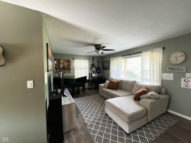 living room featuring ceiling fan, dark wood-type flooring, and a textured ceiling