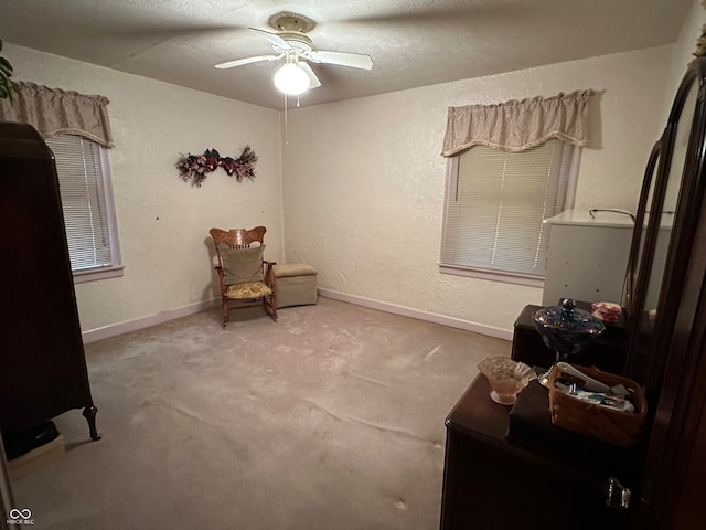 living area with a textured ceiling, carpet, and ceiling fan