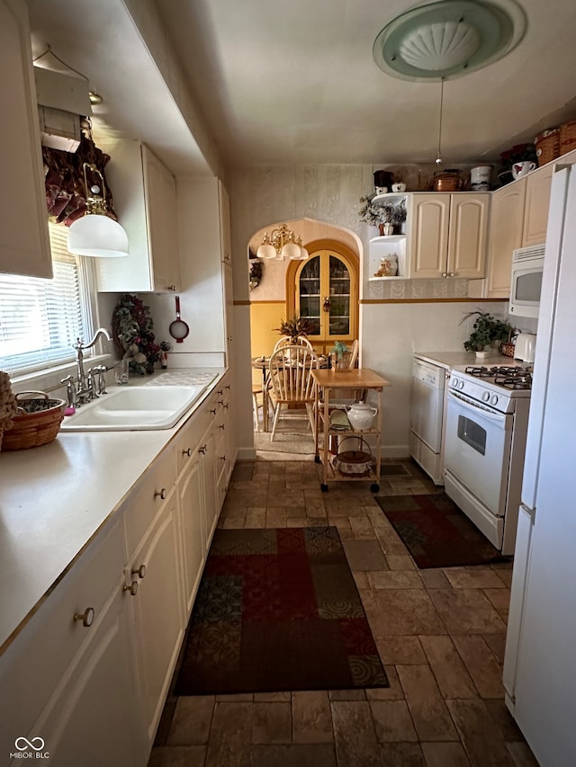 kitchen with white appliances, white cabinetry, and sink