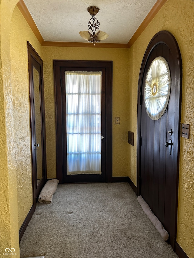 doorway with a textured ceiling, ornamental molding, and carpet floors