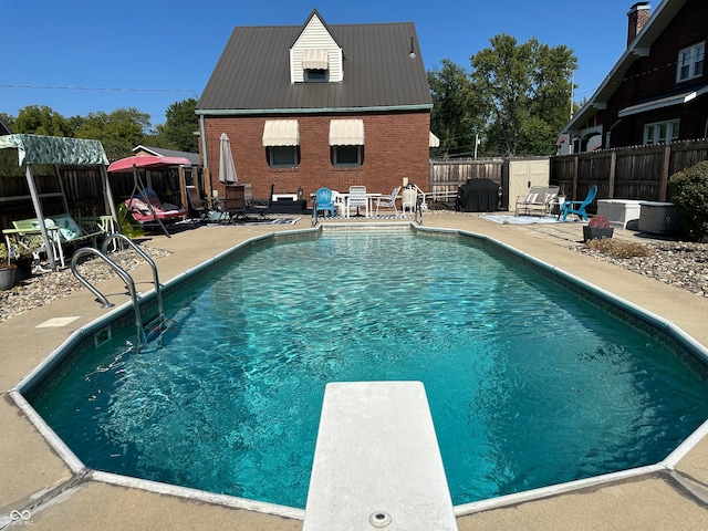 view of swimming pool featuring a patio area and a diving board