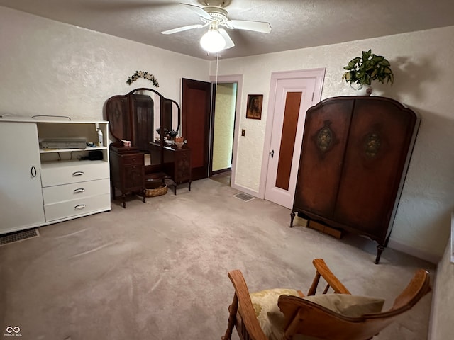 bedroom with a textured ceiling, light colored carpet, and ceiling fan