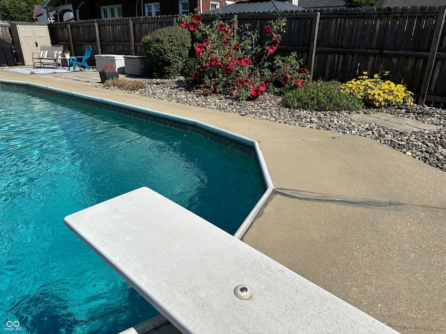 view of swimming pool with a diving board