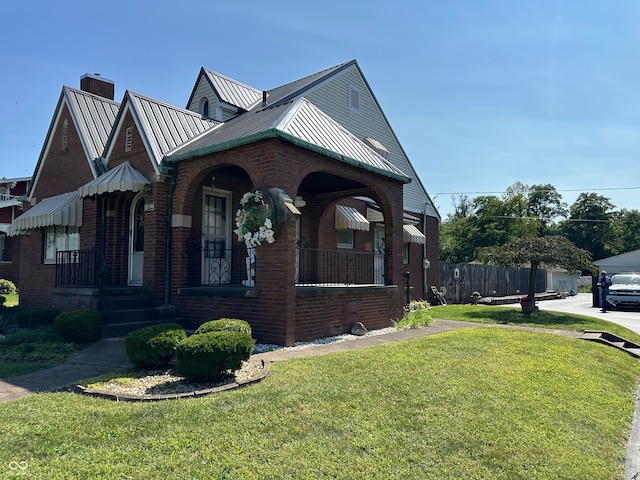 view of side of home featuring a lawn and covered porch