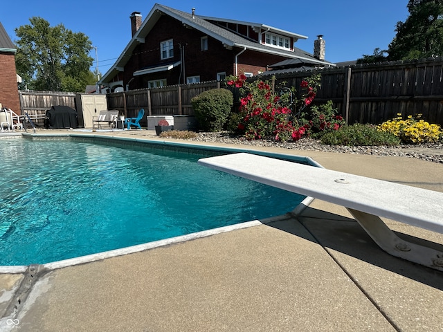 view of pool with a diving board and a patio