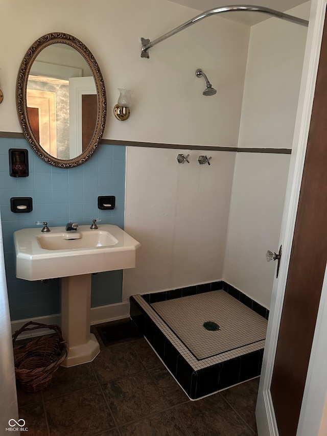 bathroom featuring tile patterned flooring, a shower, and tile walls