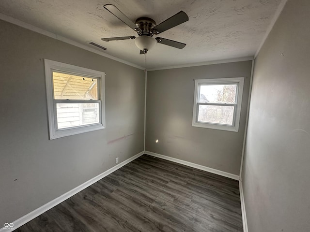 empty room with baseboards, visible vents, dark wood-style flooring, and ornamental molding