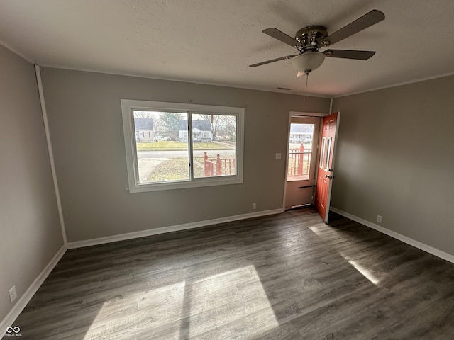 unfurnished room with visible vents, ceiling fan, baseboards, ornamental molding, and dark wood-style flooring