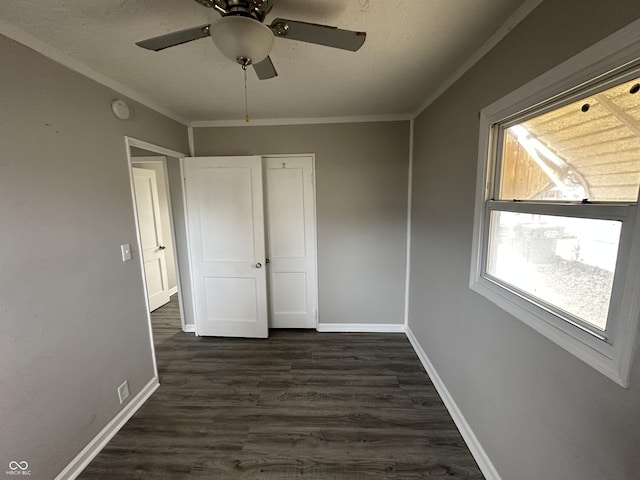 unfurnished bedroom with ceiling fan, baseboards, dark wood finished floors, and crown molding