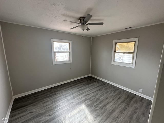 spare room featuring visible vents, baseboards, and dark wood-style flooring