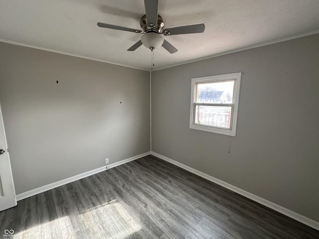 empty room with dark wood finished floors, baseboards, and ornamental molding