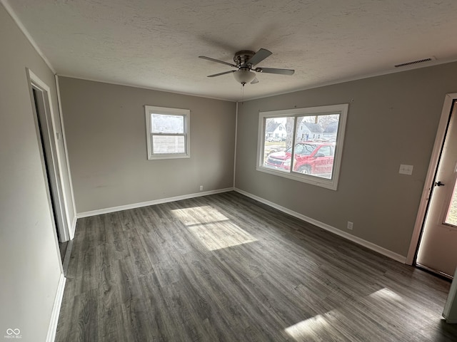 unfurnished room featuring visible vents, a textured ceiling, dark wood-type flooring, and baseboards