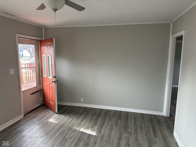 spare room featuring a textured ceiling, crown molding, baseboards, and wood finished floors