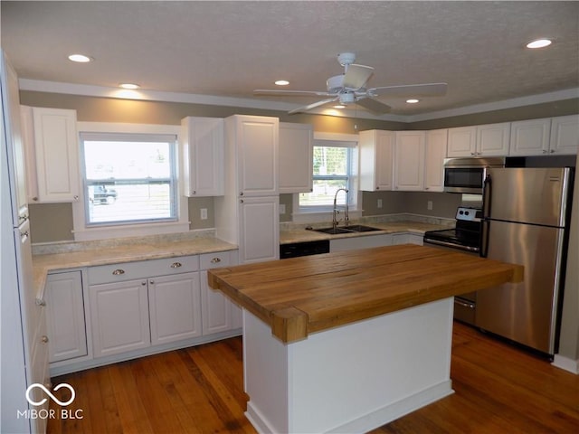 kitchen featuring butcher block countertops, a kitchen island, hardwood / wood-style floors, sink, and stainless steel appliances