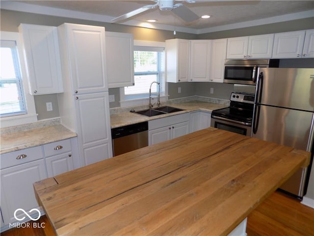 kitchen featuring ceiling fan, white cabinets, butcher block counters, sink, and stainless steel appliances