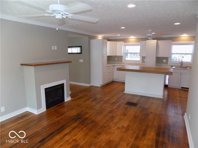 kitchen with dark hardwood / wood-style flooring, a healthy amount of sunlight, a kitchen island, and white cabinets